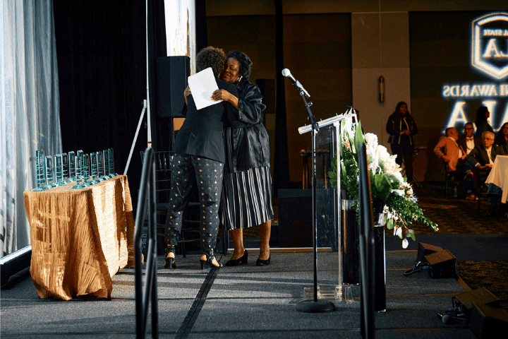 President Berenecea Johnson Eanes hugging an alum onstage at the 2024 Alumni Awards Gala